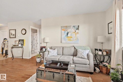 Wood-finish flooring throughout, light-toned wall paint, and a white interior door - #407 4309 33 St, Stony Plain, AB - Indoor Photo Showing Living Room