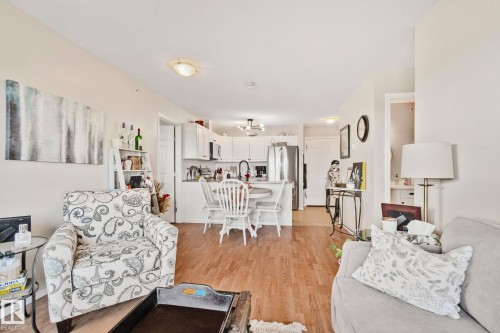Open-concept living space featuring wood-finish flooring, recessed lighting, and a kitchen with white cabinetry - #407 4309 33 St, Stony Plain, AB - Indoor Photo Showing Living Room