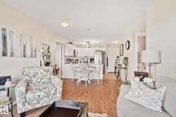 Open-concept living space featuring wood-finish flooring, recessed lighting, and a kitchen with white cabinetry - 
