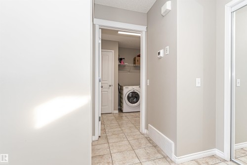 Dedicated laundry area featuring a front-load washer, tile flooring, and wire shelving - 192 Keyport Circle, Leduc, AB - Indoor Photo Showing Laundry Room