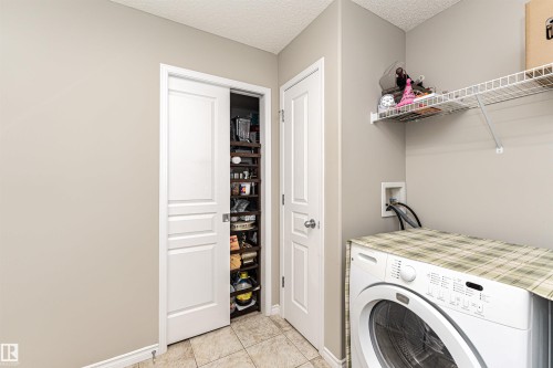 Utility area featuring tile flooring, a built-in wire shelf, and a pantry with bi-fold doors and shelving - 192 Keyport Circle, Leduc, AB - Indoor Photo Showing Laundry Room