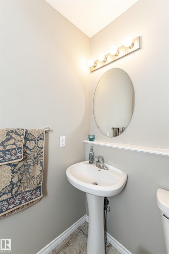Pedestal sink with chrome faucet, oval mirror, and five-bulb vanity light fixture - 192 Keyport Circle, Leduc, AB - Indoor Photo Showing Bathroom