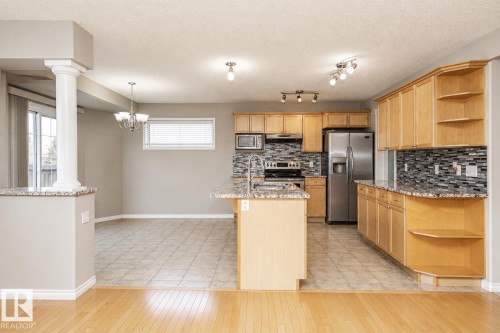 Kitchen featuring wood-finish cabinetry, stainless steel appliances, granite-style countertops, and a tile backsplash - 192 Keyport Circle, Leduc, AB - Indoor Photo Showing Kitchen