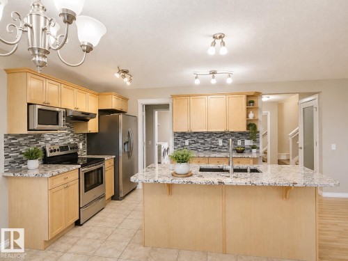 Kitchen featuring light wood cabinetry, stainless steel appliances, granite countertops, and a tile backsplash - 192 Keyport Circle, Leduc, AB - Indoor Photo Showing Kitchen With Upgraded Kitchen