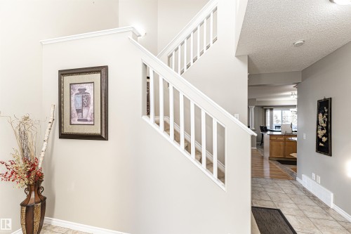 Two-story staircase with white railings, featuring carpeted steps and crown molding - 192 Keyport Circle, Leduc, AB - Indoor Photo Showing Other Room