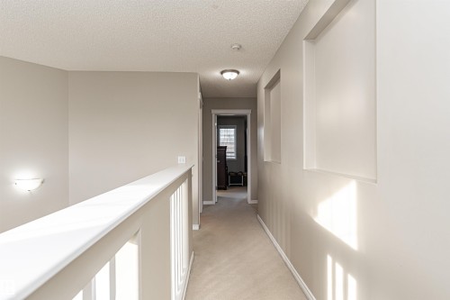 Carpeted hallway featuring an open baluster railing, recessed wall niches, and a flush mount ceiling light - 192 Keyport Circle, Leduc, AB - Indoor Photo Showing Other Room