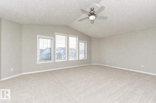 Vaulted ceiling with a ceiling fan, light-colored carpeting, and multiple windows with blinds - 192 Keyport Circle, Leduc, AB - Indoor Photo Showing Other Room