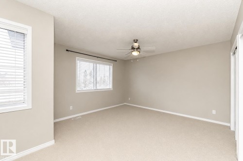 Neutral wall color, carpeted flooring, two windows with blinds, ceiling fan with integrated lighting, and white trim - 192 Keyport Circle, Leduc, AB - Indoor Photo Showing Other Room