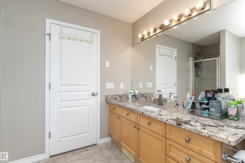 Bathroom vanity featuring a stone countertop, light wood-finish cabinetry, and a large wall-mounted mirror - 192 Keyport Circle, Leduc, AB - Indoor Photo Showing Bathroom