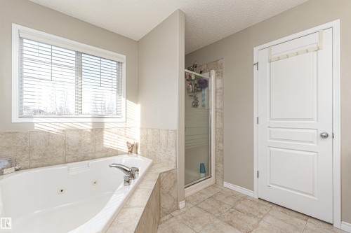 Soaking tub with chrome fixtures and surrounding tilework - 192 Keyport Circle, Leduc, AB - Indoor Photo Showing Bathroom