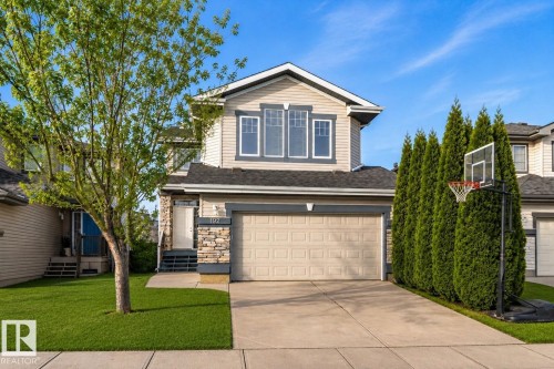 Two-story residence featuring light-toned siding, a stone facade accent, and a front-facing garage with a concrete driveway - 192 Keyport Circle, Leduc, AB - Outdoor
