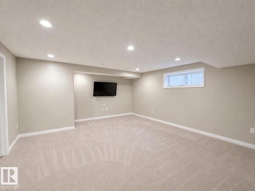 Spacious room featuring neutral wall paint, light-toned carpet, recessed lighting, and a white-framed window - 192 Keyport Circle, Leduc, AB - Indoor Photo Showing Basement