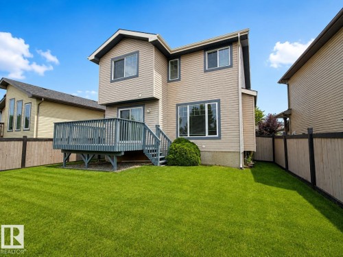 Expansive backyard with a wooden fence, large grassy area, and a wood-finished deck with stairs - 192 Keyport Circle, Leduc, AB - Outdoor With Deck Patio Veranda