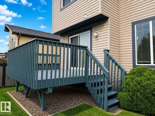 Rear deck with wood railing and steps, situated over a gravel bed - 192 Keyport Circle, Leduc, AB - Outdoor With Deck Patio Veranda