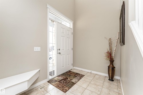 Entryway featuring a white paneled door with sidelight and transom window, light-toned tiled flooring, baseboard molding, a built-in bench, and light neutral wall paint - 192 Keyport Circle, Leduc, AB - Indoor Photo Showing Other Room