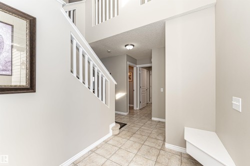 Two-story entryway featuring a white staircase with open railings, light neutral wall paint, and tile flooring - 192 Keyport Circle, Leduc, AB - Indoor Photo Showing Other Room