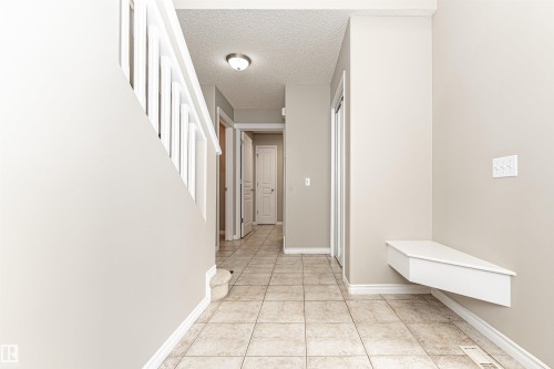 Foyer featuring tiled flooring, a built-in white bench, white baseboards, and a semi-flush mount ceiling fixture - 192 Keyport Circle, Leduc, AB - Indoor Photo Showing Other Room