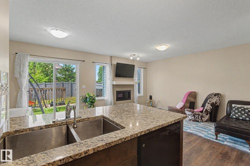 Kitchen island with a double stainless steel sink and granite countertop - 17304 73 Street Nw, Edmonton, AB - Indoor Photo Showing Kitchen With Fireplace