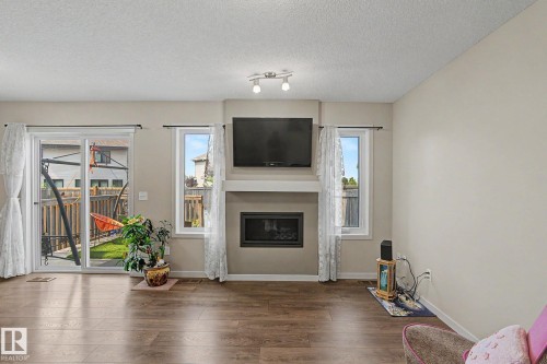 Living space featuring rich wood-finish flooring, a contemporary fireplace with a white mantel, and light neutral wall paint - 17304 73 Street Nw, Edmonton, AB - Indoor Photo Showing Living Room With Fireplace