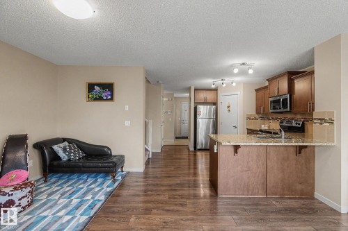 Open-concept living space featuring wood-finish flooring, a kitchen island with a light-toned countertop, and brown cabinetry - 17304 73 Street Nw, Edmonton, AB - Indoor Photo Showing Kitchen
