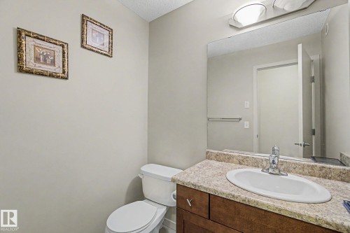 Bathroom featuring a wood-finish vanity with an integrated sink and a speckled countertop - 17304 73 Street Nw, Edmonton, AB - Indoor Photo Showing Bathroom