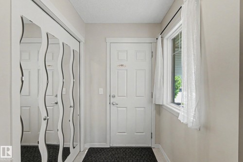 Entryway featuring a white paneled door, a single-pane window, and mirrored sliding closet doors with chrome hardware - 17304 73 Street Nw, Edmonton, AB - Indoor Photo Showing Other Room