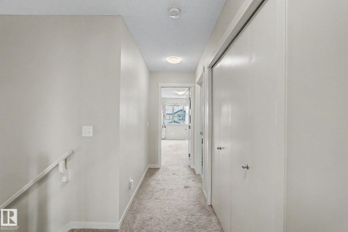 Hallway with light gray carpeting, neutral painted walls, and white bi-fold closet doors with brushed nickel hardware - 17304 73 Street Nw, Edmonton, AB - Indoor Photo Showing Other Room