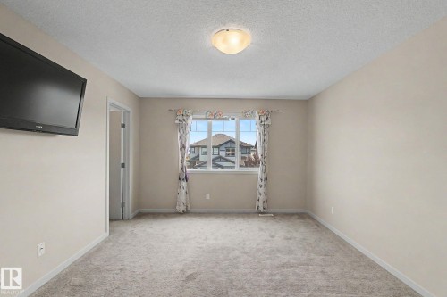 Carpeted room featuring a window with natural light, light neutral wall paint, and a flush-mount ceiling light fixture - 17304 73 Street Nw, Edmonton, AB - Indoor Photo Showing Other Room