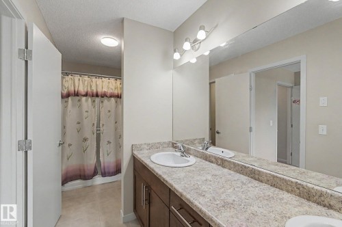 Bathroom featuring an extended vanity with dual undermount sinks, a full-width mirror, and a multi-bulb lighting fixture - 17304 73 Street Nw, Edmonton, AB - Indoor Photo Showing Bathroom