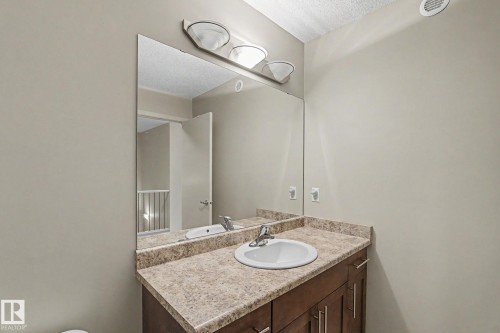 Vanity featuring a built-in sink, laminate countertop, and wood-finish cabinetry with silver-tone hardware - 17304 73 Street Nw, Edmonton, AB - Indoor Photo Showing Bathroom