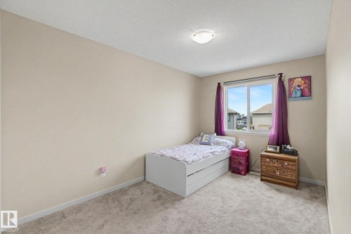 Carpeted room featuring a double-pane window with white trim, a flush mount ceiling light fixture, and neutral-toned walls - 17304 73 Street Nw, Edmonton, AB - Indoor Photo Showing Bedroom
