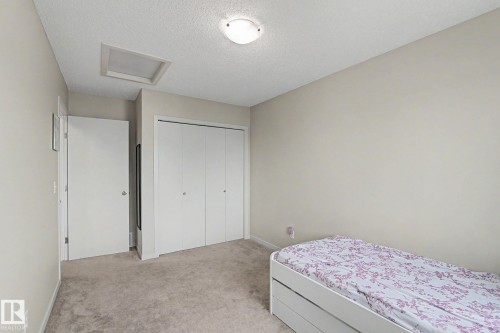 Neutral tone wall finish, plush carpet flooring, bi-fold closet doors, white trim, and a surface-mounted ceiling light fixture - 17304 73 Street Nw, Edmonton, AB - Indoor Photo Showing Bedroom