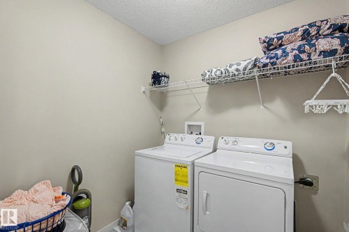 Dedicated laundry area featuring a washer and dryer, overhead wire shelving, and neutral wall finishes - 17304 73 Street Nw, Edmonton, AB - Indoor Photo Showing Laundry Room