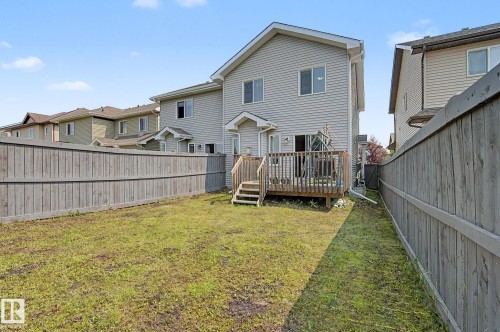 Rear exterior featuring a wooden privacy fence, a wooden deck with steps, a sliding glass door, and beige siding - 17304 73 Street Nw, Edmonton, AB - Outdoor