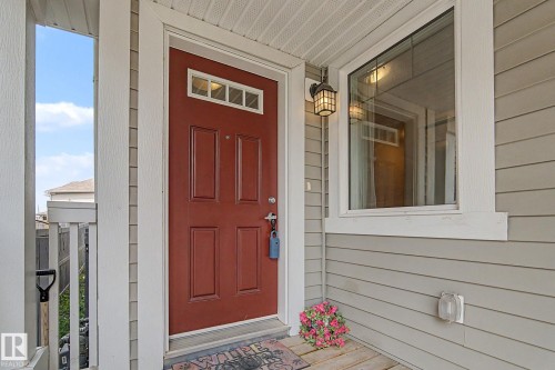 Red paneled entry door with transom window, complemented by an exterior wall sconce - 17304 73 Street Nw, Edmonton, AB - Outdoor With Exterior