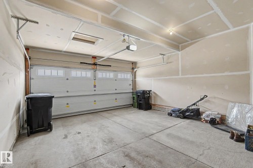 Spacious two-car garage featuring a concrete floor, an overhead door with window inserts, and an automatic garage door opener - 17304 73 Street Nw, Edmonton, AB - Indoor Photo Showing Garage
