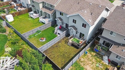 Fenced backyard with green lawn, featuring a fire pit area, raised garden beds, and a private deck - 17304 73 Street Nw, Edmonton, AB - Outdoor