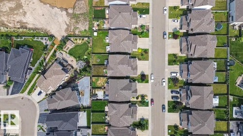 Aerial perspective showcasing a residential street with uniform homes featuring gabled roofs and individual green spaces - 17304 73 Street Nw, Edmonton, AB -  With View