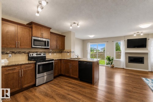 Kitchen featuring wood-finish cabinetry, stainless steel appliances, and granite-look countertops - 17304 73 Street Nw, Edmonton, AB - Indoor Photo Showing Kitchen With Fireplace With Stainless Steel Kitchen
