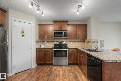 Kitchen featuring wood-finish flooring, granite countertops, and wood cabinetry - 17304 73 Street Nw, Edmonton, AB - Indoor Photo Showing Kitchen With Stainless Steel Kitchen With Double Sink