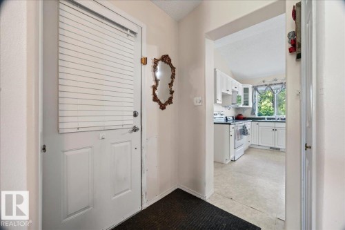 White paneled door with horizontal blinds, leading to a kitchen featuring white cabinetry, a large window, a white range, and light-toned flooring - 121 51205 Range Road 195, Rural Beaver County, AB - Indoor Photo Showing Other Room