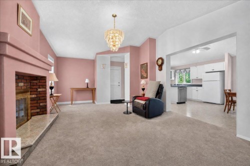 Brick fireplace with a stone hearth, recessed ceiling, chandelier, and a wide entryway to the kitchen - 121 51205 Range Road 195, Rural Beaver County, AB - Indoor