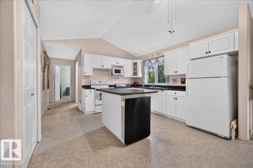 Kitchen featuring white cabinetry, a central island, a stainless steel microwave, a white range, and a white refrigerator - 121 51205 Range Road 195, Rural Beaver County, AB - Indoor Photo Showing Kitchen
