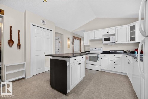 Kitchen featuring white cabinetry, dark countertops, a central island, and an integrated microwave - 121 51205 Range Road 195, Rural Beaver County, AB - Indoor Photo Showing Kitchen