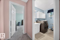 Full-size laundry appliances, white vanity with cabinet storage, window for natural light, and overhead white cabinetry - 