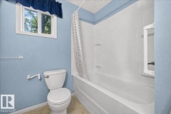Bathtub with integrated shelving, white toilet, and window with natural light - 