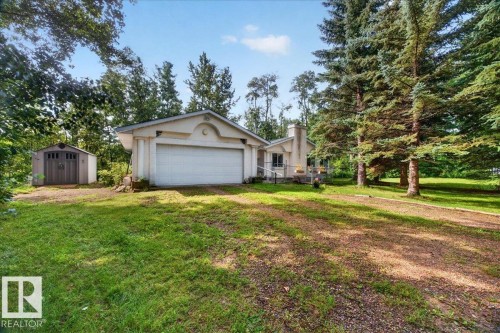 Exterior featuring an attached two-car garage, a detached storage shed, and mature evergreen trees - 121 51205 Range Road 195, Rural Beaver County, AB - Outdoor