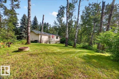 Expansive grassy yard with mature trees, a fire pit, and a rear deck with railing - 121 51205 Range Road 195, Rural Beaver County, AB - Outdoor
