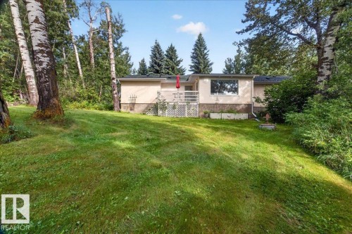 Green lawn with mature deciduous and evergreen trees, featuring a light-toned exterior with a white deck railing - 121 51205 Range Road 195, Rural Beaver County, AB - Outdoor