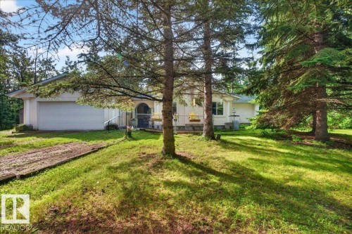 Single-story residence with an attached garage, featuring a covered entry and a sloped lawn with mature trees - 121 51205 Range Road 195, Rural Beaver County, AB - Outdoor